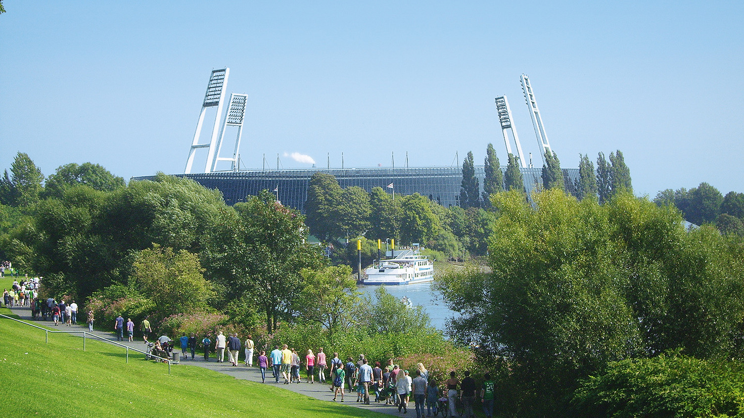An einem sonnigen Tag machen sich Menschen auf den Weg zum Weserstadion.