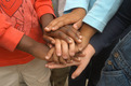 Das Foto zeigt Kinderhände in verschiedener Hautfarbe, die solidarisch übereinandergelgt werden