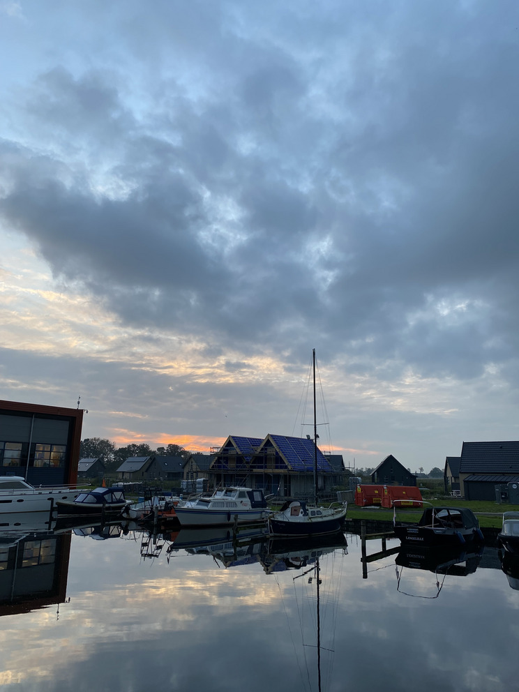 Ein Sonnenuntergang über einem Hafen der sich im Wasser spiegelt.