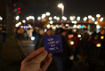 Das Foto zeigt eine Lichterketten-Demo. Im Vordergrund hält eine Hand ein Schild mit der Aufschrift "Nie wieder ist jetzt" hoch