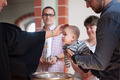 Ein Baby wird am Taufbecken einer Kirche getauft.