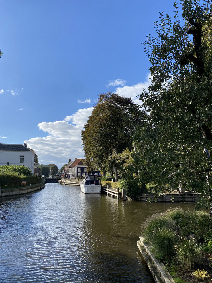 Ein Boot liegt etwas entfernt am Ufer und wartet vor einer Schleuseneinfahrt.