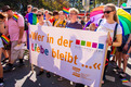 Das Foto zeigt die CSD-Demo in Bremen. Teilnehmer halten ein Banner hoch mit der Aufschrift "Wer in der Liebe bleibt..."