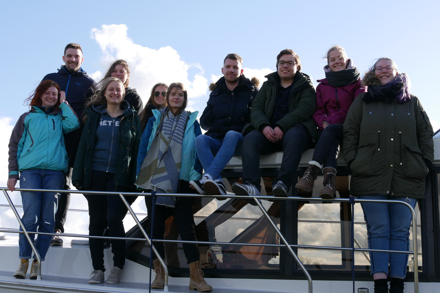 Eine Gruppe Menschen steht auf und vor der Seite eines Bootes für ein Gruppenfoto.