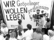 Das Foto zeigt eine Gruppe Aktivisten 1990 vor einem Plakat mit der Aufschrift "Wir Gröpelinger wollen gemeinsam leben"