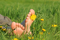 Auf dem Foto sieht man nackten Füße eines Menschen, der entspannt auf einer Sommerwiese liegt