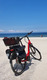 Ein Fahrrad am weißen Strand vor einem blauen Meer. Es ist ein strahlend sonniger Tag.