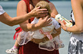 Das Foto zeigt die Taufe eines Kleinkindes und eine Patin mit einer Taufkerze.