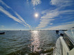 Das Boot fährt auf einen See hinaus der von vielen Segelbooten befahren wird. Die Sonne spiegelt sich auf dem Wasser.