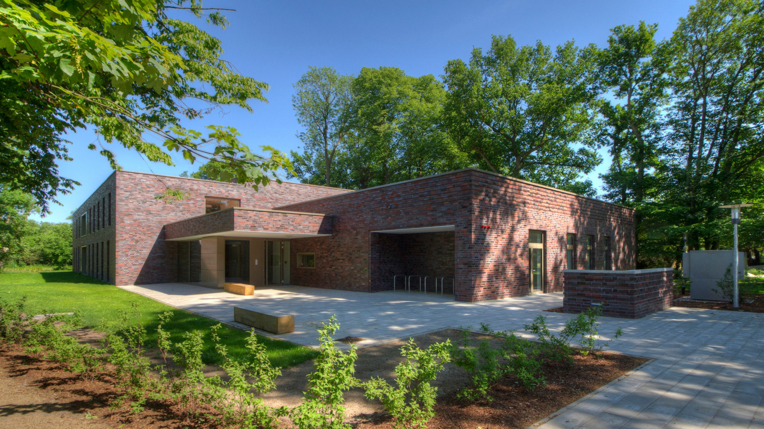 Der Neubau der Kita, von grünen Bäumen umringt an einem sonnigen Tag.